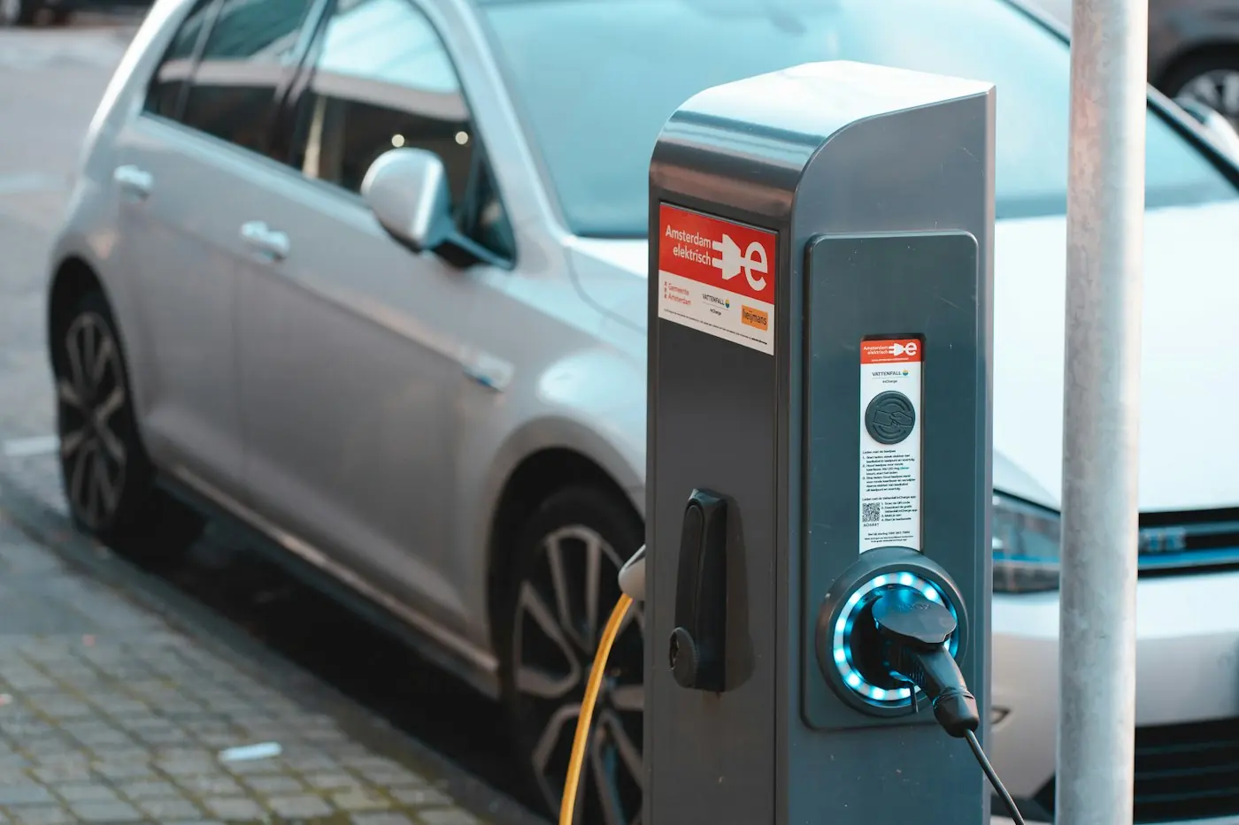 Public AC charging post connected to a parked electric car